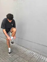 Remera negra con efecto gastado, corte oversize, mangas cortas y estampa en la espalda con palmeras, ángel en una hamaca y texto "Paradise Holiday Brixton".