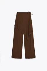 Pantalón marrón de tiro medio con cintura elástica y pierna ancha. Presenta una superposición tipo pareo ajustable con lazadas.