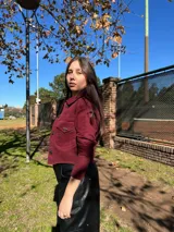 Chaqueta corta de jean color bordó, con cuello camisero, mangas largas y bolsillos con solapa en el pecho.