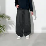 Pantalón jean negro de corte ultra baggy, con diseño de costuras curvas en el frente.
