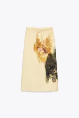 Falda midi color crema con estampado floral difuminado en tonos marrones y verdes. Tiene cintura ajustable con lazos y abertura en la parte trasera. Cierre con cremallera oculta en la costura.