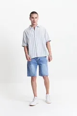 Camisa de manga corta con corte oversize, a rayas verticales blancas y grises, con cuello clásico y cierre frontal con botones. Confeccionada en algodón.