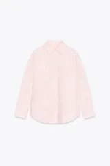 Camisa manga larga color rosa pálido con cuello solapa y cierre frontal con botones. Detalle de bordados perforados engomados con motivos florales. Corte recto.