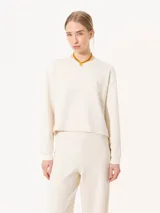 Buzo de punto color crema con lurex y mangas largas con puños ajustados.