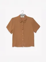 Camisa negra de manga corta en crepé de viscosa suave, con cuello camisero y detalle floral en la botonadura central.