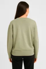 Sweater color verde oliva con estampado de flor blanca, de algodón con cuello redondo y corte holgado.