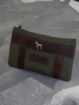 Sobre tipo cartuchera color borgoña, de lona con terminaciones en cuero marrón. Tiene cierre superior y aplique de cuero con el logo de la marca.