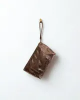 Sobre de cuero color marrón metalizado con bolsillo externo y correa de mano desmontable.