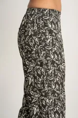Pantalón recto con estampado de hojas color blanco sobre fondo negro, con cintura elástica y bolsillos laterales.