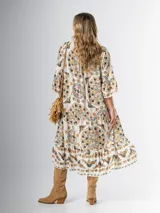 Vestido midi de algodón italiano, color blanco con estampado boho chic en tonos naranja, marrón y verde. Tiene corte oversized, mangas 3/4 con volados y cinturón de soga trenzada con hebilla circular.