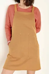 Vestido jumper color ocre, de corte recto, con breteles anchos y bolsillos frontales.