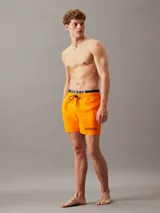 Short de baño naranja de poliéster reciclado, con cintura elástica negra con logo de Calvin Klein y cordón ajustable.