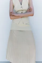 Falda midi color crema, de tiro alto con cintura elástica y tejido plisado semitransparente.
