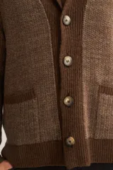 Cardigan tejido color marrón con cuello smoking, cierre con botones y bolsillos delanteros.