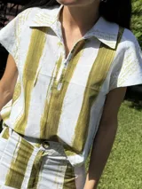 Top con cuello tipo polo y cierre parcial con cremallera, con estampado de rayas verticales y texto.