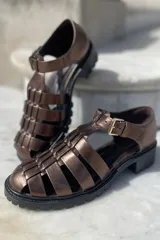 Sandalias de cuero color cobre con diseño de tiras entrecruzadas, hebilla lateral y suela track color negro.