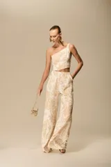 Mono largo de fiesta con estampado barroco en tonos beige y blanco. Presenta escote asimétrico, cintura marcada y pantalón de pierna ancha.