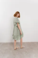 Vestido corto color beige confeccionado en algodón, con escote en V con detalles bordados, mangas cortas amplias con volados y falda con ruedo en volado.