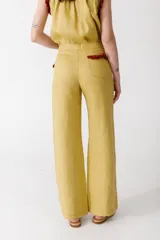 Pantalón de jean azul oscuro, de corte acampanado, con bolsillos delanteros con detalle de volados.