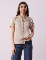 Blusa color beige de gasa con cuello fruncido, escote en V con lazo y mangas cortas con volados.