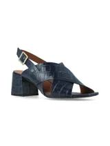 Sandalias negras de charol con tiras cruzadas, tacón cuadrado y pulsera al tobillo con hebilla metálica.