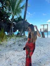 Vestido midi de microtul rojo con estampado de rosas y hojas verdes, escote en V con encaje negro y breteles finos regulables en la espalda.