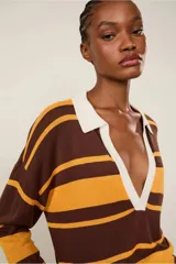 Top de punto de manga larga con cuello polo blanco, escote en V profundo y rayas horizontales en tonos marrón y mostaza. Los puños y el bajo son acanalados.