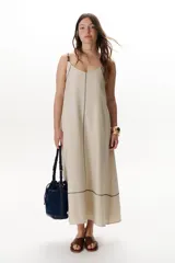 Vestido largo color crudo con breteles finos y costuras a la vista en color azul.