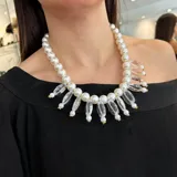 Collar de perlas plásticas blancas con detalles de resina transparente y herrajes dorados.