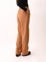 Pantalón marrón de vestir, de corte recto, con pinzas en la cintura y cierre con botón.