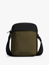 Cartera tipo reporter Tommy Hilfiger color verde militar con detalles en negro. Presenta correa ajustable, bolsillo frontal con cierre y logo metálico de la marca.