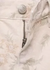 Pantalón de jean de corte wide leg con estampado floral en tonos pastel. Tiene tiro alto, cinco bolsillos, trabillas y cierre frontal con cremallera y botón.