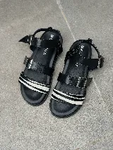 Sandalias bajas negras de cuero con dos tiras regulables y agarre en el tobillo. Tira frontal con estampado cebra.