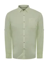 Camisa de manga larga color verde claro, confeccionada en popelina de algodón orgánico. Tiene cuello camisero, bolsillo de parche en el pecho izquierdo, botones de madera y protección solar UPF +20.