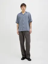 Camisa de manga corta con estampado geométrico en tonos azul y beige, cuello resort y cierre de botones. Confeccionada en tejido dobby 100% algodón.