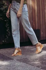 Sandalias de cuero color marrón con plataforma de cuña y tira con hebilla al tobillo.