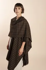 Ruana marrón con diseño a cuadros blancos, terminación envivada y flecos cortos.
