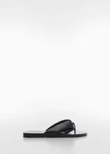 Sandalia negra de cuero con tachuelas decorativas y punta redonda.