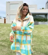 Buzo largo con cuello alto de polar color crema y cuerpo con estampado de cuadros en tonos celeste, amarillo y blanco.