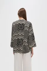 Kimono de poliéster con estampado geométrico en blanco y negro, mangas 3/4, corte holgado y cuello en V.
