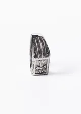 Anillo signet rectangular de acero quirúrgico pulido, con cruz estilizada en alto relieve y grabados geométricos en los laterales.