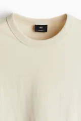 Remera color crema de corte recto, cuello redondo y mangas cortas.