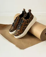 Zapatillas bajas de cuero con estampado animal print de leopardo, cordones negros y suela blanca.