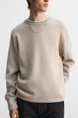 Jersey color beige de punto con cuello redondo y manga larga.