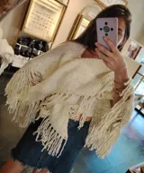 Ruana de tejido crochet color crema con flecos largos.