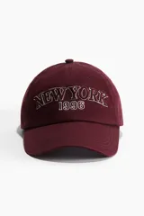 Gorra de béisbol color borgoña con bordado frontal de la leyenda "New York 1996" en color blanco.