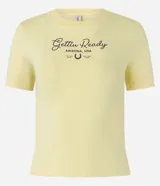 Remera corta color amarillo pastel, de algodón, con cuello redondo y mangas cortas. Estampado frontal con la frase "Gettin Ready Arizona, USA" y un herraje.