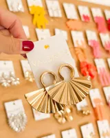 Caravanas colgantes doradas, con forma de abanico plisado, unidas a un aro superior.