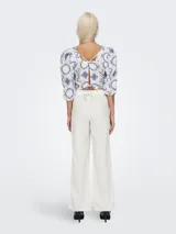 Top corto blanco con estampado de flores azules, cuello cuadrado y mangas cortas abullonadas.