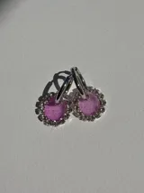 Par de aros colgantes con argolla de acero quirúrgico, dije circular de resina negra y borde de strass plateado.